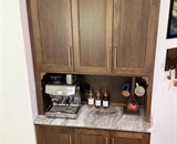 Custom beverage center with stained wood cabinetry and stone countertop in Loretto, MN kitchen remodel