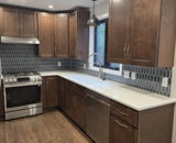 Remodeled Big Lake, MN kitchen with dark wood cabinets, white countertops and tile backsplash
